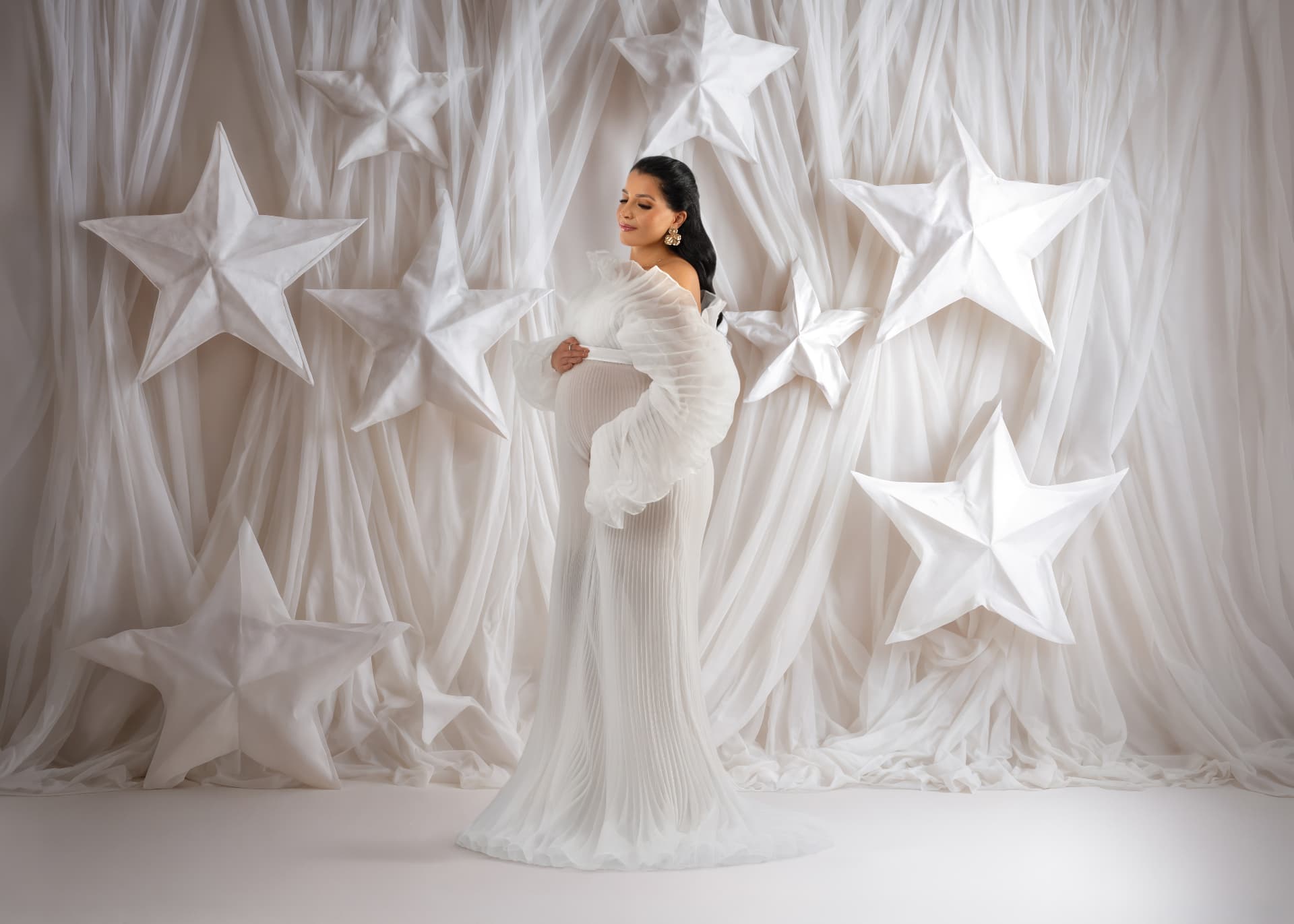 Babybauch-Shooting in weißem Kleid vor Tüll-Sternen-Kulisse